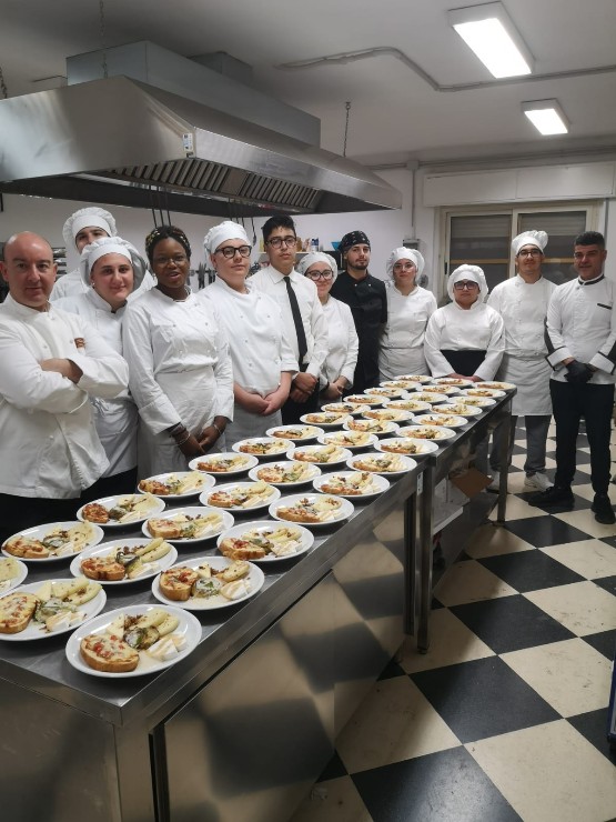 Lo staff di cucina posa con una linea di piatti pronti da servire a tavola